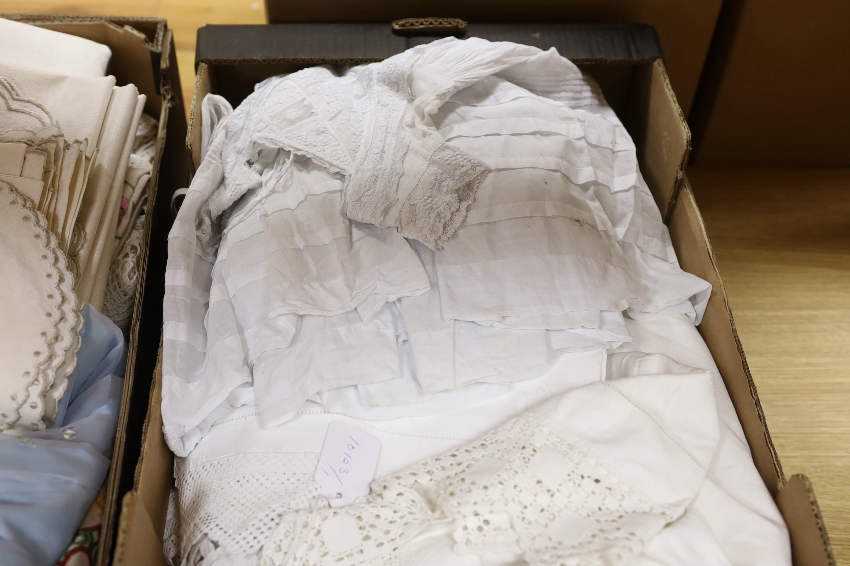 A 19th century white worked and hand made lace christening gown with a collection of table linens and a collection of coloured embroidered linens and a child's dress (2 boxes)